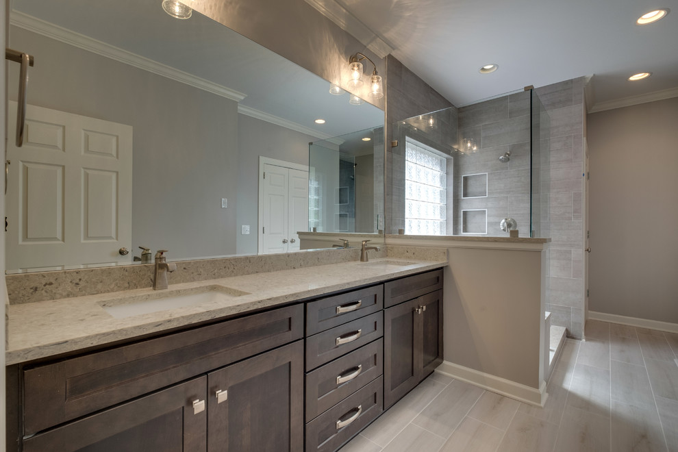 Photo of a large contemporary master bathroom in Nashville with shaker cabinets, dark wood cabinets, a two-piece toilet, gray tile, porcelain tile, grey walls, plywood floors, an undermount sink, engineered quartz benchtops, white floor, an open shower and grey benchtops.