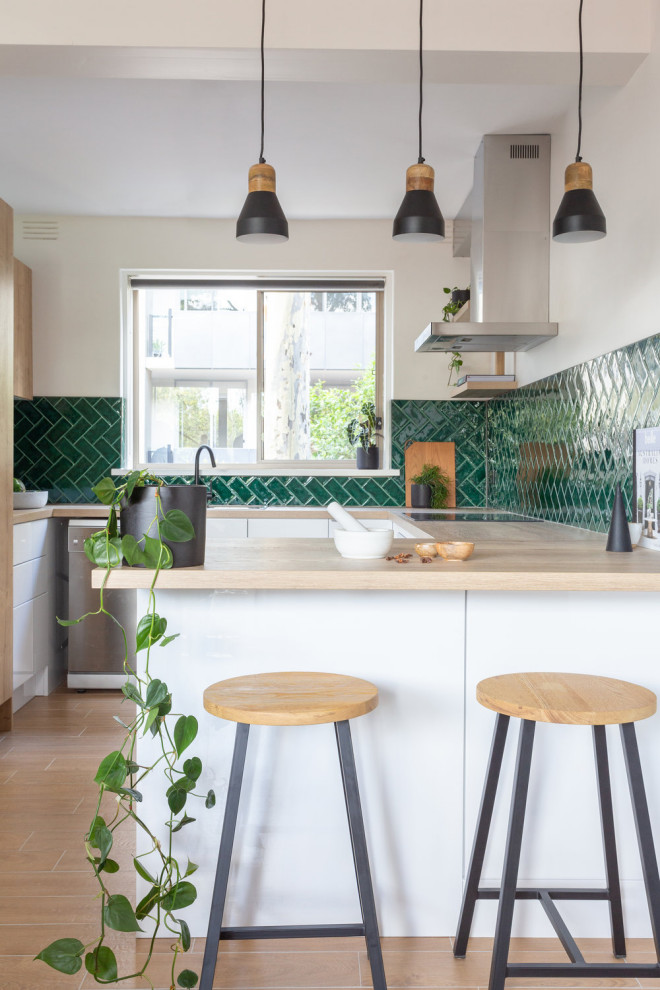 Design ideas for a small modern u-shaped open plan kitchen in Melbourne with white cabinets, laminate benchtops, green splashback, ceramic splashback and porcelain floors.