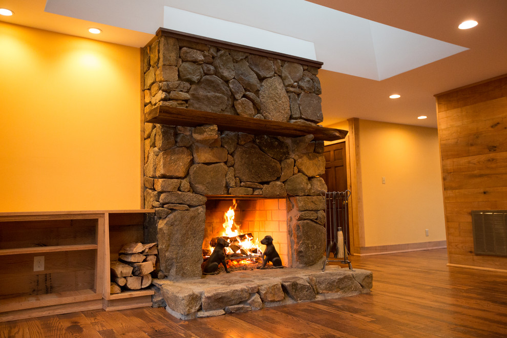 Large mountain style formal and open concept dark wood floor home design photo with orange walls, a standard fireplace, a stone fireplace and no tv