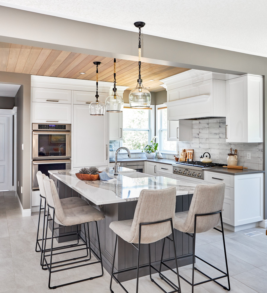 Design ideas for a transitional l-shaped kitchen in Toronto with a farmhouse sink, shaker cabinets, white cabinets, quartz benchtops, grey splashback, panelled appliances, with island, grey floor and grey benchtop.