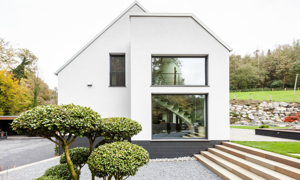 This is an example of a mid-sized contemporary two-storey stucco white exterior in Essen with a gable roof.