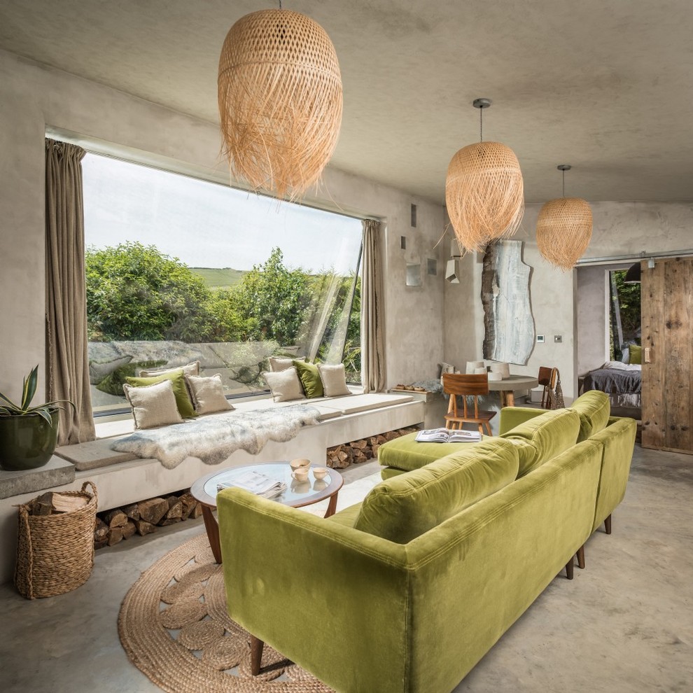 Small rustic open plan living room in Cornwall with beige walls, concrete flooring, a corner fireplace, a concrete fireplace surround and beige floors.
