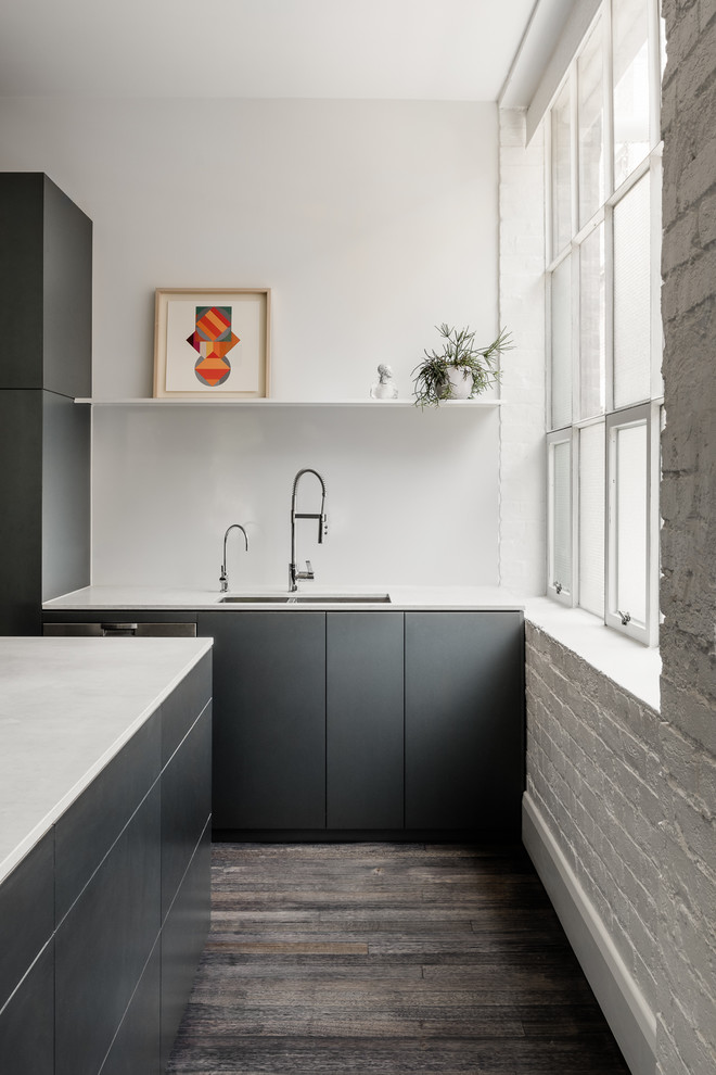 This is an example of a contemporary kitchen in Melbourne with a double-bowl sink, flat-panel cabinets, grey cabinets, white splashback, dark hardwood floors, brown floor and white benchtop.
