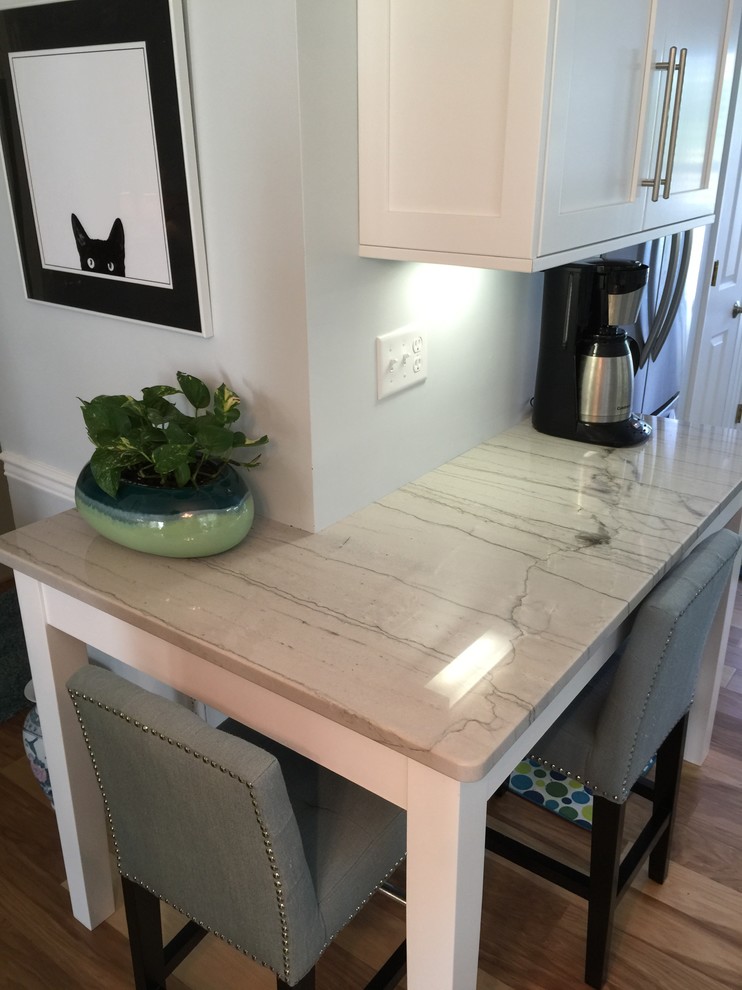 Inspiration for a medium tone wood floor kitchen remodel with a double-bowl sink, flat-panel cabinets, white cabinets, quartzite countertops, blue backsplash, glass tile backsplash and stainless steel appliances