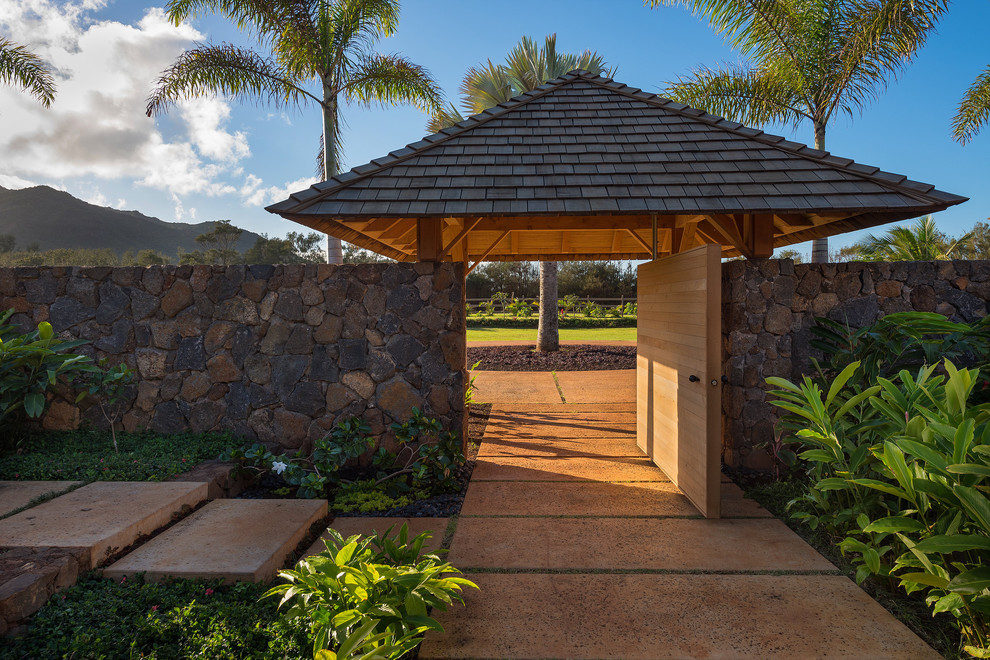 Design ideas for a tropical entryway in Hawaii with concrete floors, a pivot front door and a medium wood front door.