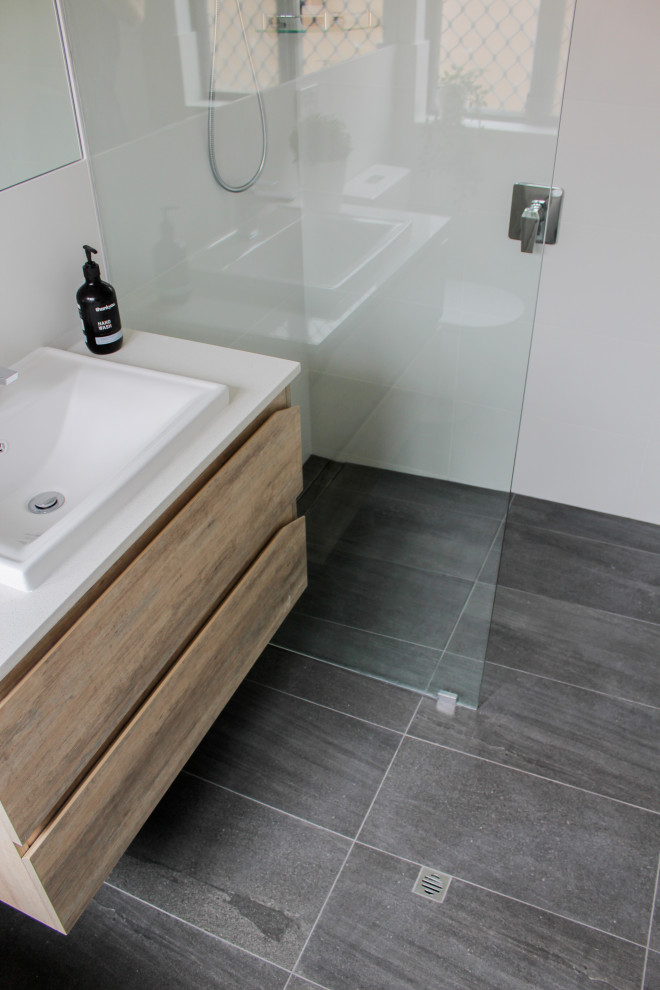 Photo of a small 3/4 bathroom in Perth with flat-panel cabinets, light wood cabinets, an open shower, a one-piece toilet, white tile, ceramic tile, white walls, porcelain floors, a vessel sink, engineered quartz benchtops, black floor and white benchtops.