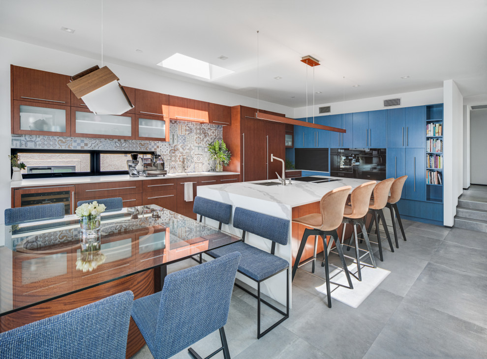 Inspiration for a modern galley eat-in kitchen in Orange County with an undermount sink, flat-panel cabinets, quartz benchtops, multi-coloured splashback, porcelain splashback, black appliances, porcelain floors, with island, grey floor and white benchtop.