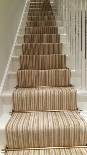 Mid-sized transitional carpeted u-shaped staircase in London with carpet risers and wood railing.