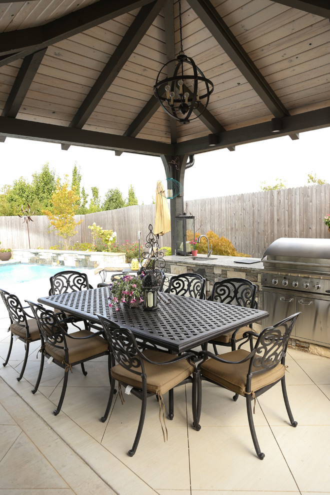 Example of a large transitional backyard tile patio kitchen design with a gazebo