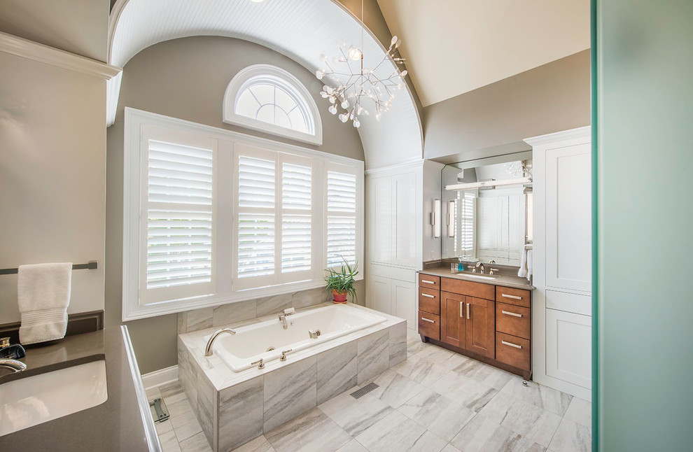Design ideas for a large transitional master bathroom in Cleveland with shaker cabinets, medium wood cabinets, a drop-in tub, beige walls, an undermount sink, a curbless shower, a two-piece toilet, brown tile, stone slab, marble floors and solid surface benchtops.