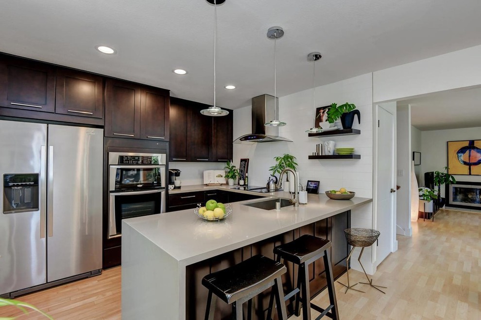 Mid-sized modern single-wall eat-in kitchen in San Francisco with an undermount sink, shaker cabinets, dark wood cabinets, quartz benchtops, stainless steel appliances, light hardwood floors, with island, beige floor and grey benchtop.