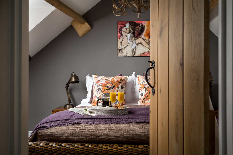 This is an example of a mid-sized country master bedroom in Gloucestershire with grey walls.