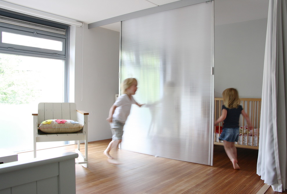 Contemporary gender-neutral nursery in Amsterdam with white walls and medium hardwood floors.