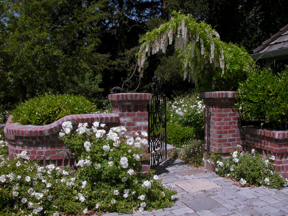 Design ideas for a mid-sized traditional backyard formal garden for summer in San Francisco with natural stone pavers and a metal fence.
