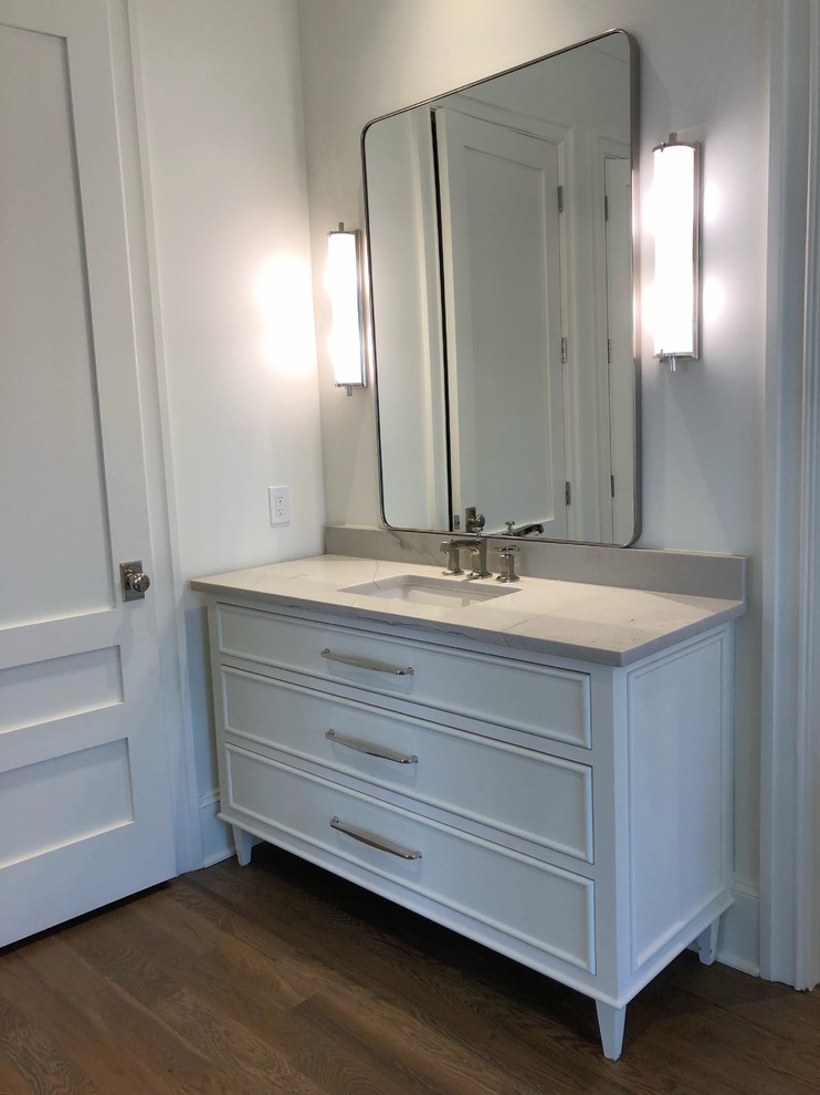 Design ideas for a mid-sized country 3/4 bathroom in Atlanta with furniture-like cabinets, white cabinets, white walls, light hardwood floors, an undermount sink, marble benchtops, brown floor and white benchtops.
