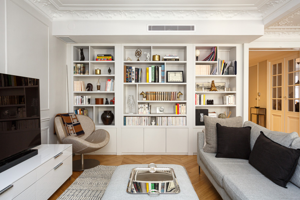 Exempel på ett mellanstort modernt allrum med öppen planlösning, med ett bibliotek, vita väggar, ljust trägolv, en fristående TV och beiget golv