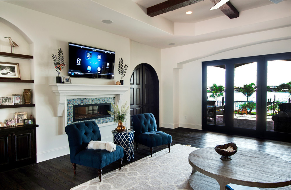 Photo of a large mediterranean open concept living room in Tampa with white walls, dark hardwood floors, a ribbon fireplace, a tile fireplace surround and a wall-mounted tv.
