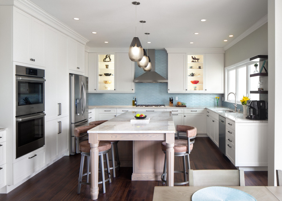 Large transitional u-shaped eat-in kitchen in Raleigh with a double-bowl sink, shaker cabinets, white cabinets, quartzite benchtops, blue splashback, glass tile splashback, stainless steel appliances, dark hardwood floors, with island, brown floor and white benchtop.