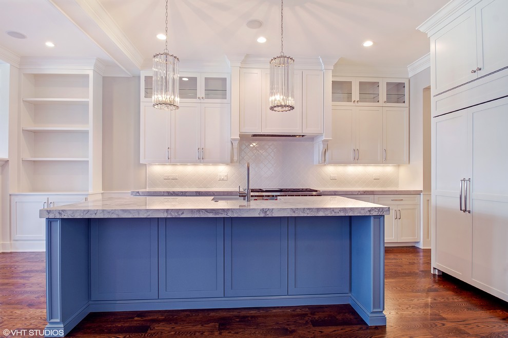 Inspiration for a transitional kitchen in Chicago with a farmhouse sink, shaker cabinets, blue cabinets, granite benchtops, white splashback, ceramic splashback, panelled appliances, medium hardwood floors and with island.