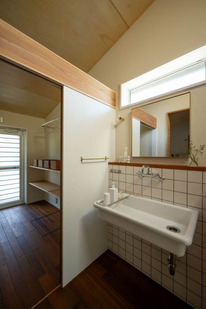 Свежая идея для дизайна: маленький туалет с белыми фасадами, белой плиткой, керамогранитной плиткой, белыми стенами, темным паркетным полом, коричневым полом, встроенной тумбой, деревянным потолком и обоями на стенах для на участке и в саду - отличное фото интерьера