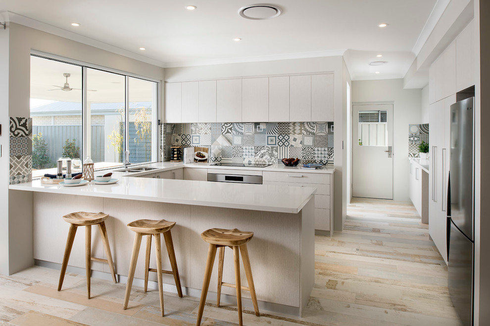 This is an example of a mid-sized scandinavian u-shaped eat-in kitchen in Perth with a double-bowl sink, flat-panel cabinets, white cabinets, multi-coloured splashback, ceramic splashback, stainless steel appliances, light hardwood floors and a peninsula.