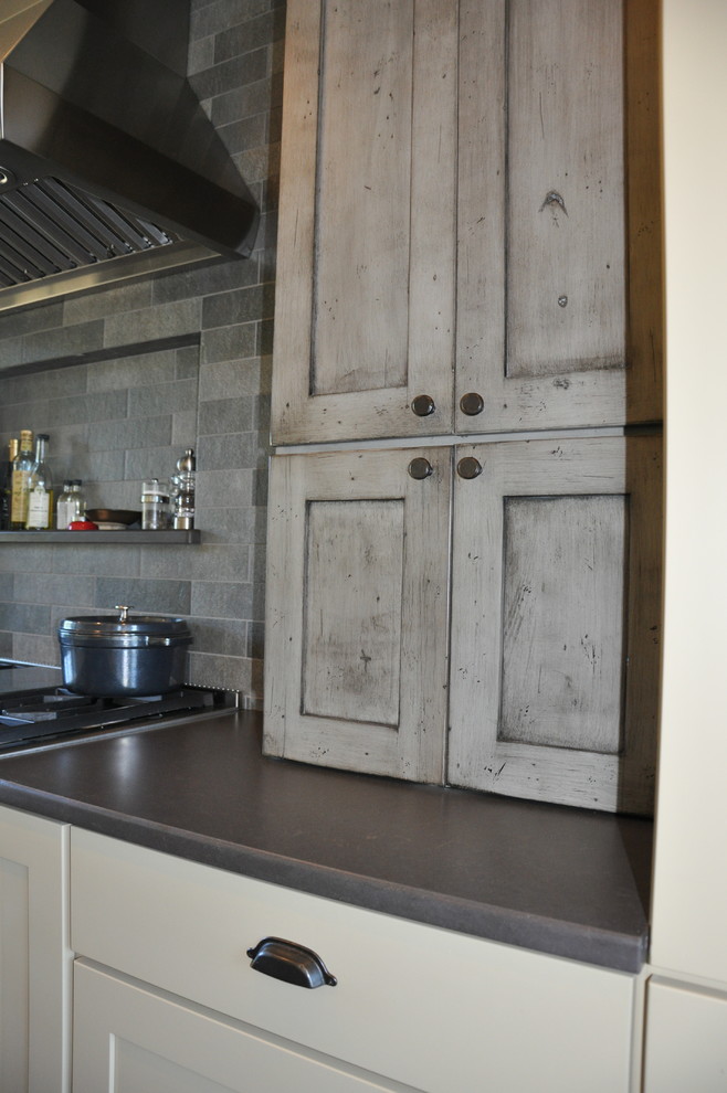 Inspiration for a large rustic l-shaped eat-in kitchen remodel in Seattle with shaker cabinets, distressed cabinets, quartz countertops, gray backsplash, stone tile backsplash, stainless steel appliances and an island