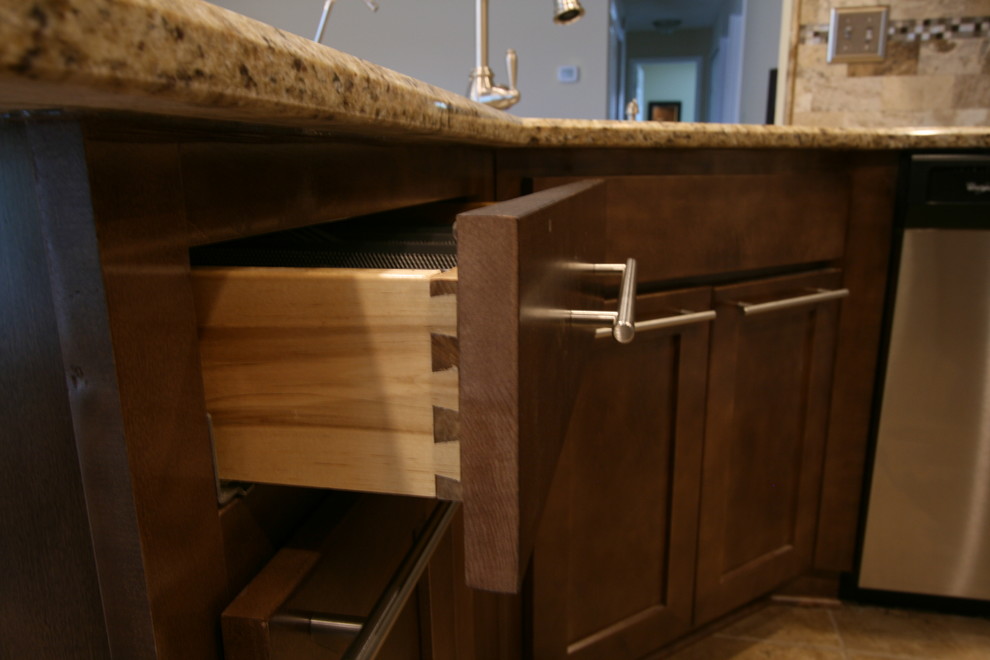 Eat-in kitchen - mid-sized transitional l-shaped porcelain tile eat-in kitchen idea in Jacksonville with an undermount sink, shaker cabinets, brown cabinets, granite countertops, beige backsplash, stone tile backsplash, stainless steel appliances and a peninsula