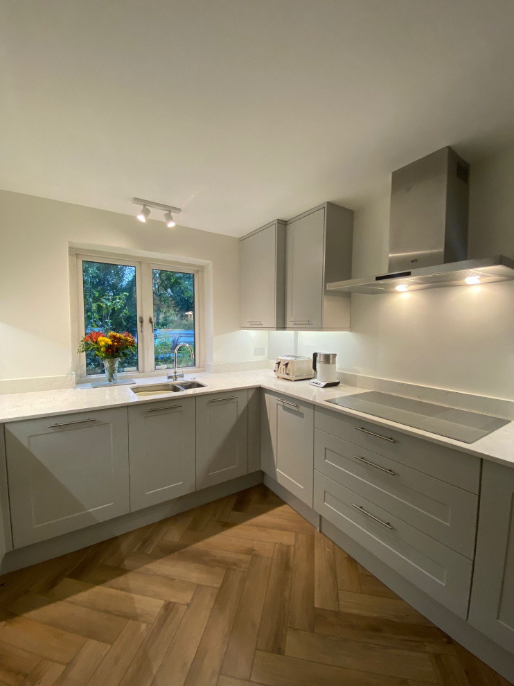 Cette image montre une cuisine design de taille moyenne avec un plan de travail en quartz, parquet clair et un sol marron.