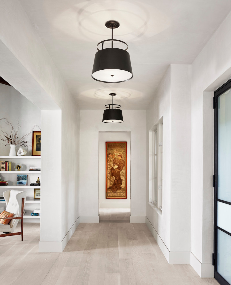 Photo of a mid-sized midcentury hallway in Austin with white walls, light hardwood floors and white floor.