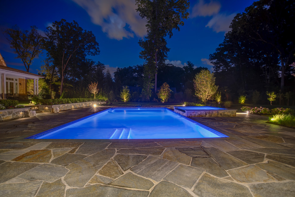 Photo of a mid-sized country backyard rectangular lap pool in New York with a hot tub and natural stone pavers.