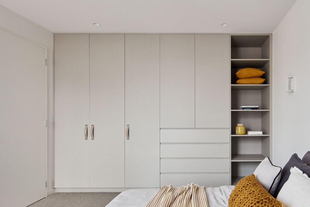 Inspiration for a large contemporary gender-neutral storage and wardrobe in Melbourne with flat-panel cabinets, grey cabinets, carpet and grey floor.