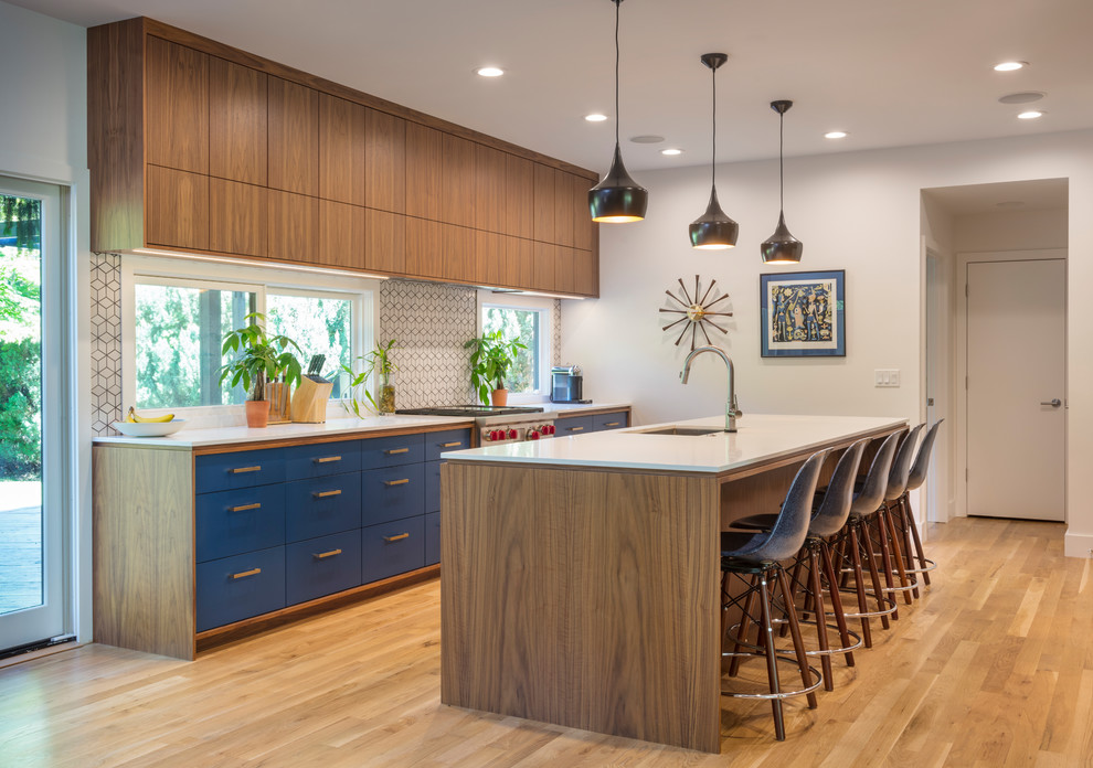 Design ideas for a midcentury kitchen in Kansas City with an undermount sink, flat-panel cabinets, blue cabinets, window splashback, stainless steel appliances, light hardwood floors and with island.