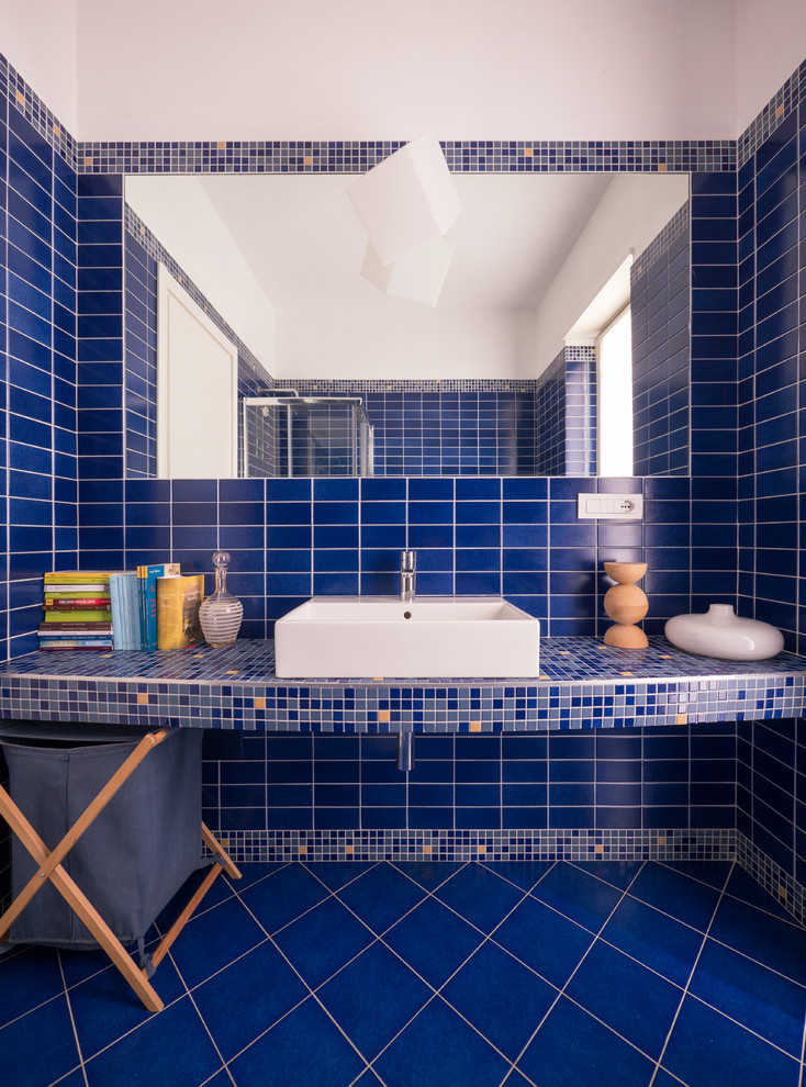 Photo of a small contemporary 3/4 bathroom in Milan with a corner shower, a two-piece toilet, blue tile, mosaic tile, blue walls, ceramic floors, a trough sink, concrete benchtops, blue floor and a sliding shower screen.