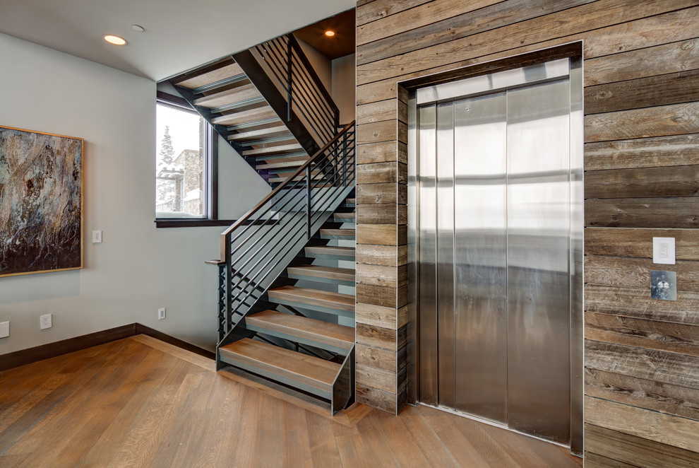 Large modern wood u-shaped staircase in Salt Lake City with open risers and metal railing.