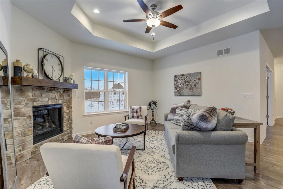 Medium sized open plan games room in Milwaukee with white walls, a corner fireplace, a stone fireplace surround, brown floors and a drop ceiling.