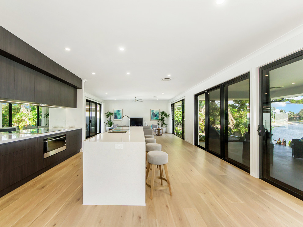 Contemporary kitchen in Gold Coast - Tweed with flat-panel cabinets, dark wood cabinets, stainless steel appliances, light hardwood floors and with island.