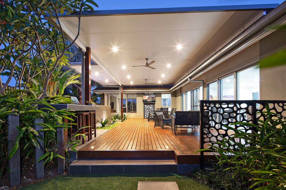 Inspiration for a tropical backyard partial sun garden in Sunshine Coast with decking, a fire feature and a wood fence.