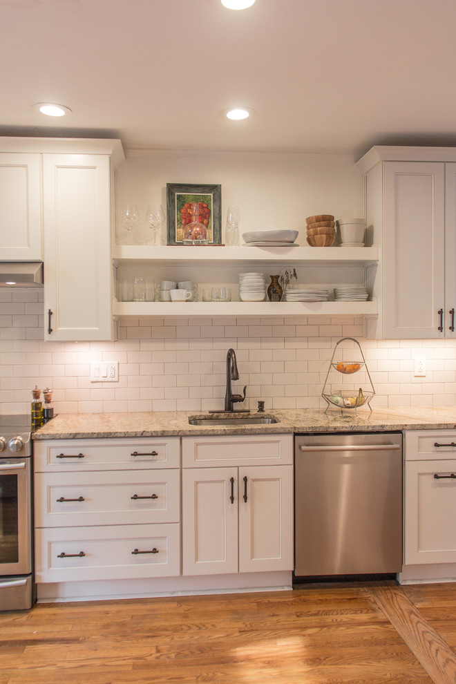 Example of a transitional medium tone wood floor kitchen design with granite countertops, subway tile backsplash and stainless steel appliances