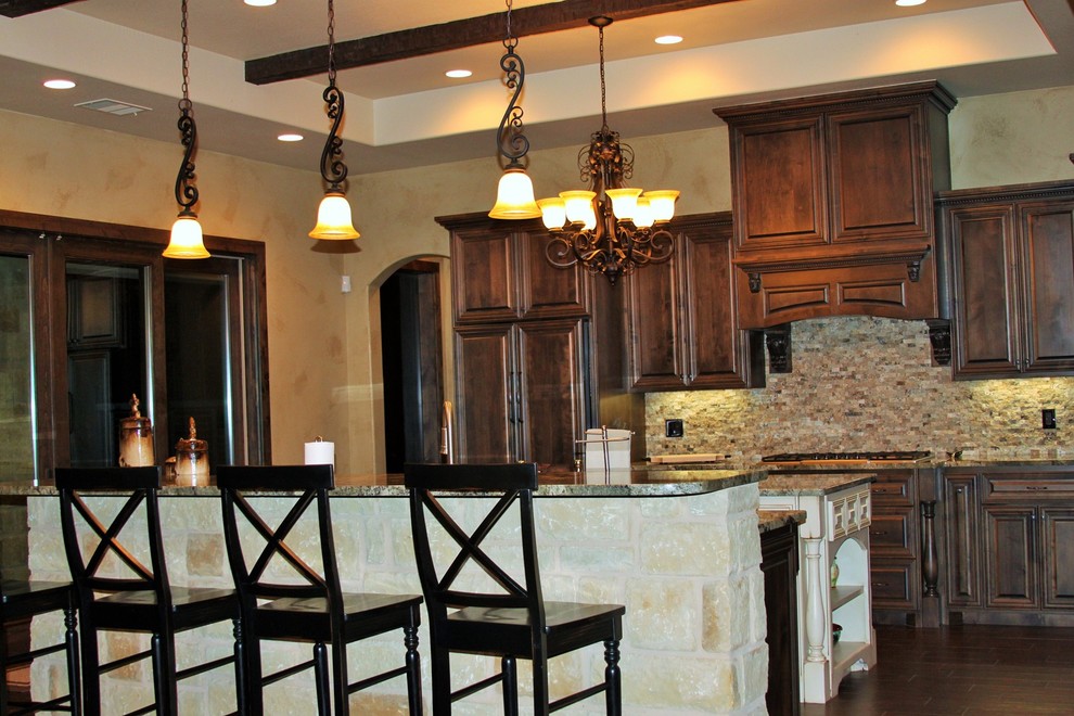 Example of a large l-shaped limestone floor open concept kitchen design in Austin with a drop-in sink, dark wood cabinets, granite countertops, beige backsplash, ceramic backsplash, stainless steel appliances and an island
