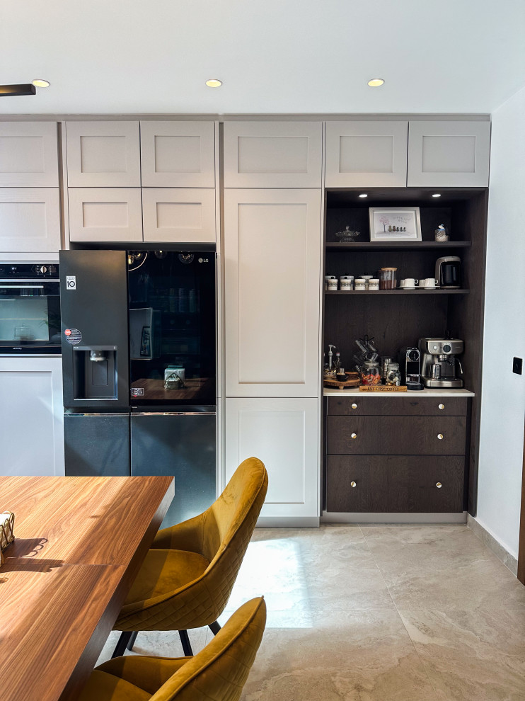 Photo of a large traditional l-shaped kitchen/diner in London with a built-in sink, shaker cabinets, blue cabinets, quartz worktops, white splashback, engineered quartz splashback, integrated appliances, porcelain flooring, an island, beige floors, white worktops and feature lighting.