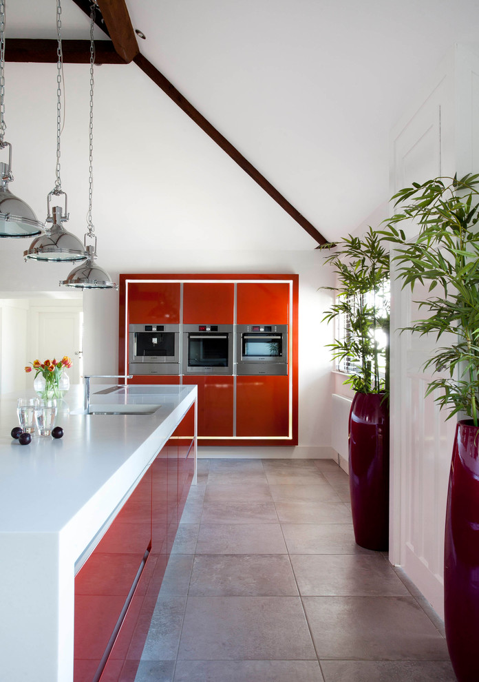 Photo of a large contemporary l-shaped separate kitchen in Belfast with an undermount sink, flat-panel cabinets, orange cabinets, solid surface benchtops, white splashback, stone slab splashback, stainless steel appliances, ceramic floors, with island and grey floor.