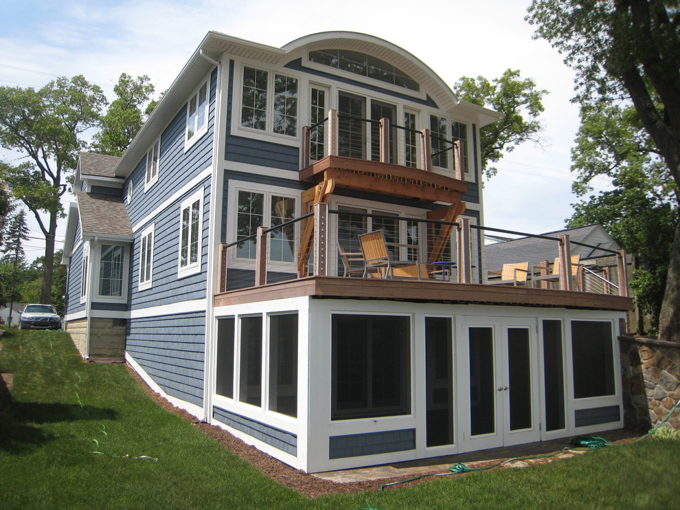 Design ideas for a mid-sized beach style three-storey blue house exterior in Grand Rapids with vinyl siding, a hip roof and a mixed roof.