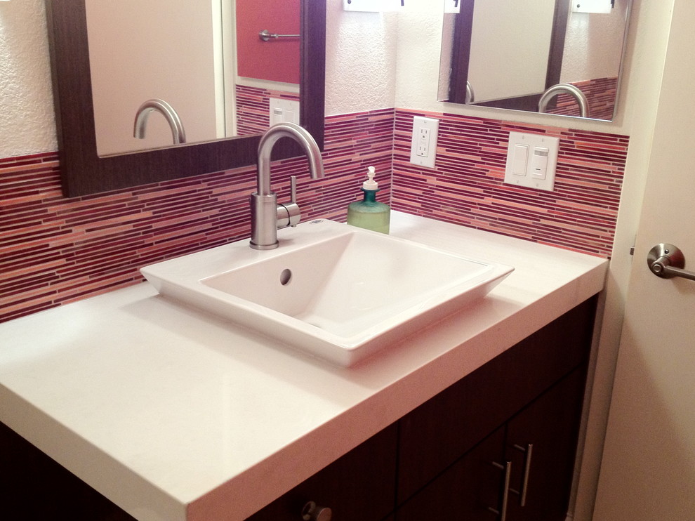 This is an example of a small contemporary powder room in San Francisco with a vessel sink, flat-panel cabinets, dark wood cabinets, engineered quartz benchtops, a two-piece toilet, red tile, matchstick tile and porcelain floors.
