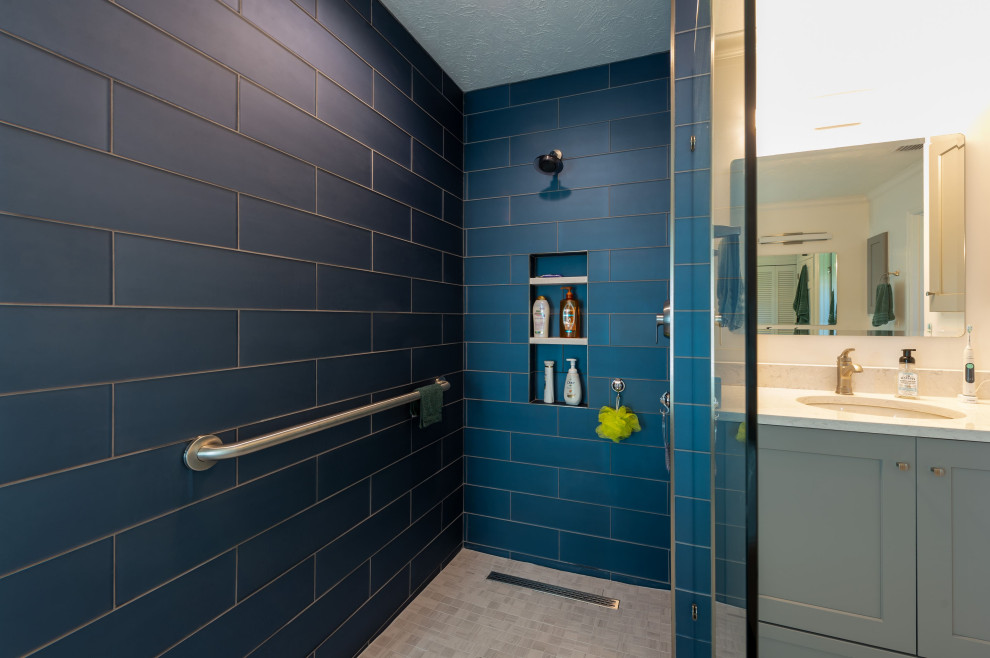 Photo of a modern wet room bathroom in Tampa with recessed-panel cabinets, grey cabinets, a japanese tub, blue tile, ceramic tile, white walls, laminate floors, multi-coloured floor, an open shower, a single vanity and a built-in vanity.