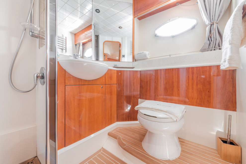 Foto på ett litet maritimt grå badrum med dusch, med släta luckor, bruna skåp, en hörndusch, vita väggar, mellanmörkt trägolv, ett integrerad handfat, bänkskiva i kvartsit, beiget golv och dusch med gångjärnsdörr