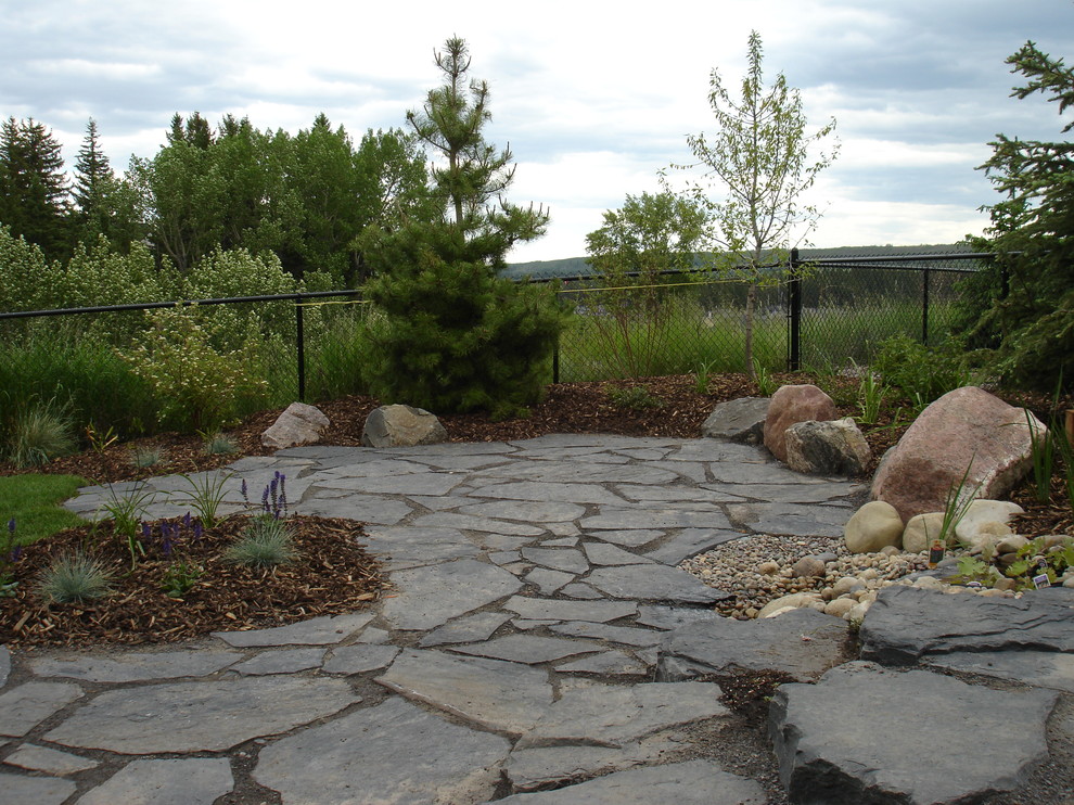 Design ideas for a mid-sized arts and crafts backyard patio in Calgary with a water feature, natural stone pavers and no cover.