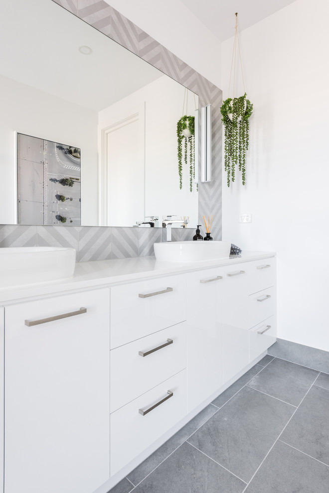 Inspiration for a mid-sized contemporary master bathroom in Melbourne with flat-panel cabinets, white cabinets, a corner shower, a two-piece toilet, gray tile, ceramic tile, white walls, porcelain floors, a vessel sink, engineered quartz benchtops, grey floor, a hinged shower door and white benchtops.