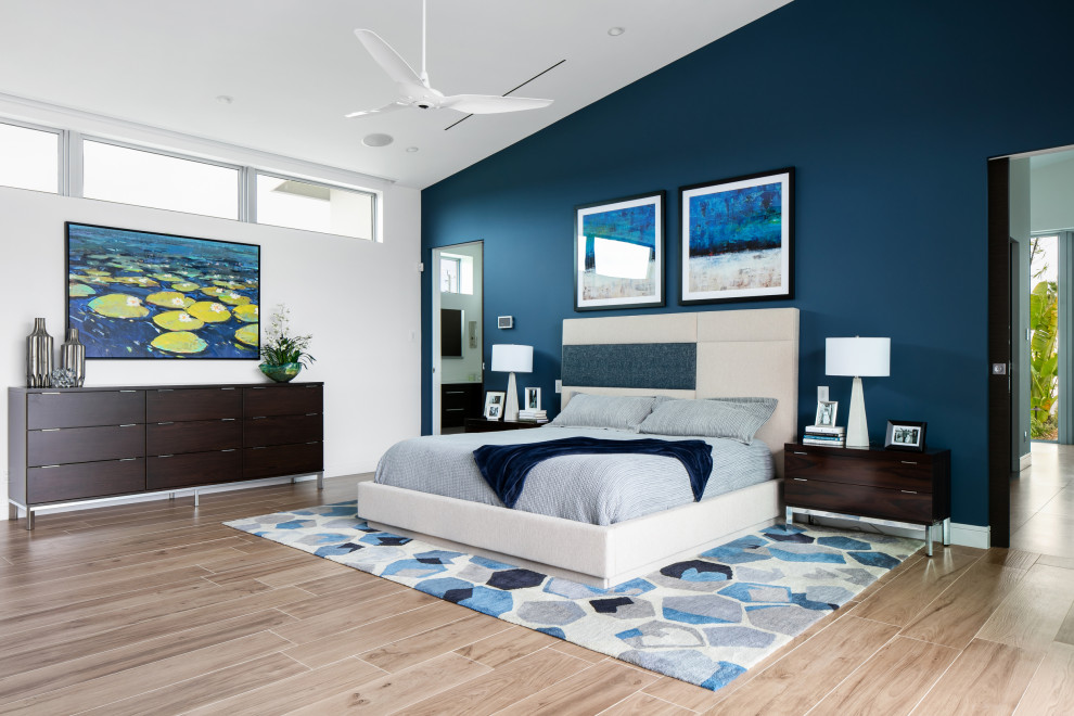Geräumiges Modernes Hauptschlafzimmer mit weißer Wandfarbe, Porzellan-Bodenfliesen, Gaskamin, gefliester Kaminumrandung, braunem Boden und gewölbter Decke in Tampa