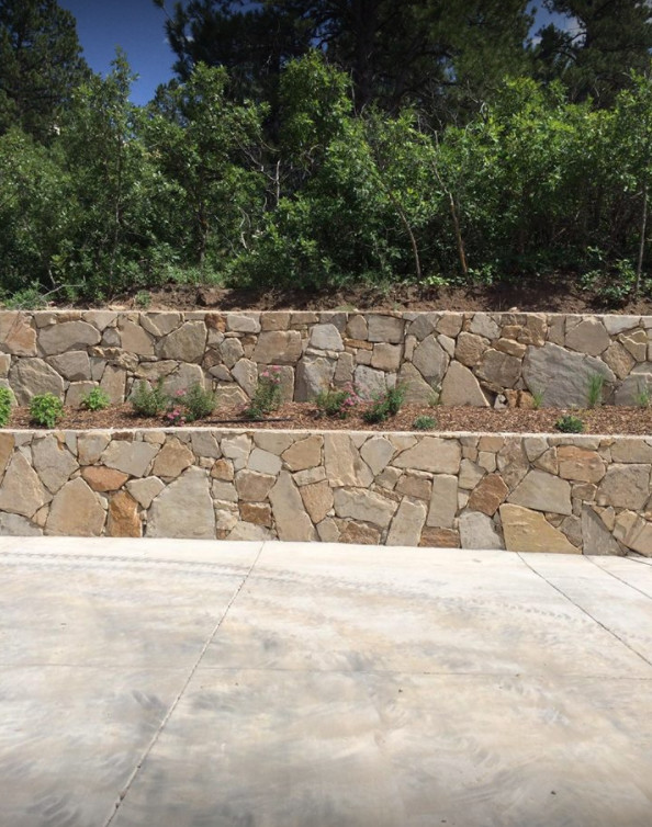 Photo of a large traditional backyard full sun driveway in Denver with a retaining wall.
