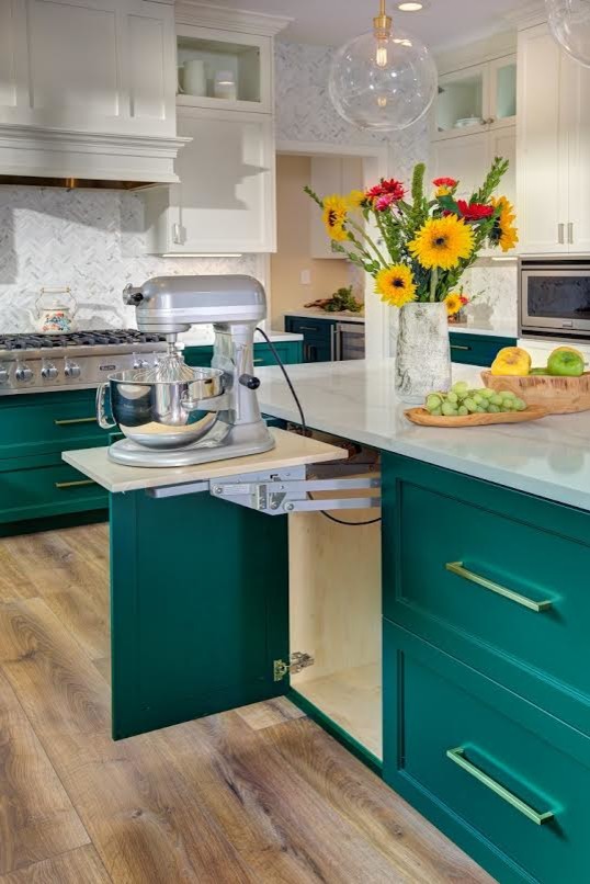 This is an example of a mid-sized transitional l-shaped eat-in kitchen in Sacramento with an undermount sink, green cabinets, grey splashback, stainless steel appliances, medium hardwood floors, with island, brown floor, shaker cabinets, quartz benchtops, porcelain splashback and white benchtop.